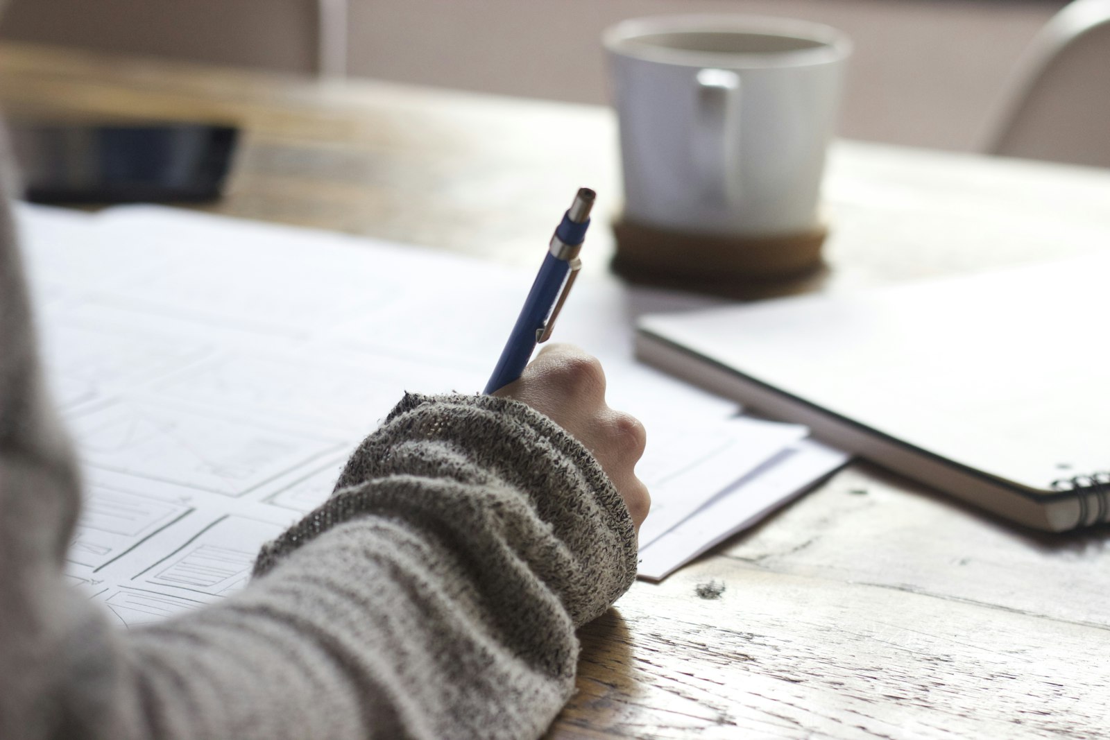 Student writing in a notebook beside a laptop